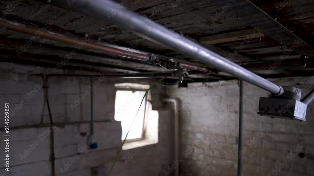 Dolly shot of an old and creepy basement. Tubes, pipelines, dirty walls and a dusty window in the background. Dolly shot of an old and creepy basement. Tubes, pipelines, dirty walls and a dusty window in the background.
