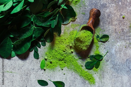 Fresh Moringa / Muringa leaves and powder in a wooden scoop, selective focus photo