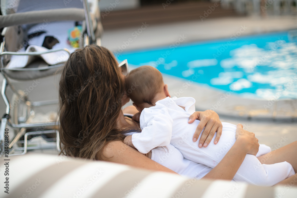 Obraz premium Woman relax near luxury poolside with baby