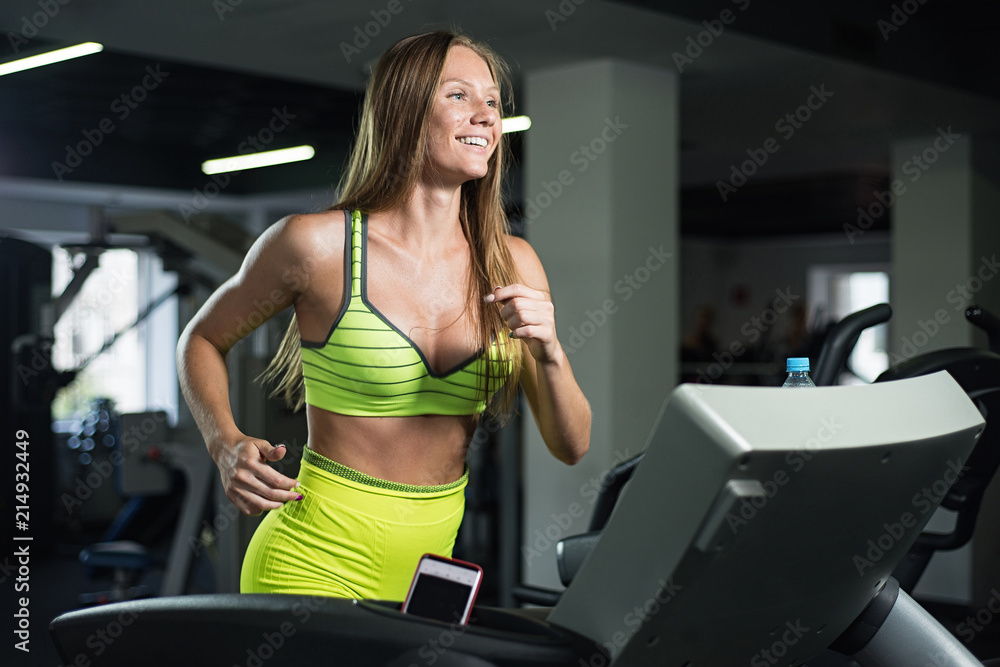 Beautiful girl running on treadmill in gym, healthy lifestyle concept Beautiful girl running on treadmill in gym, healthy lifestyle concept