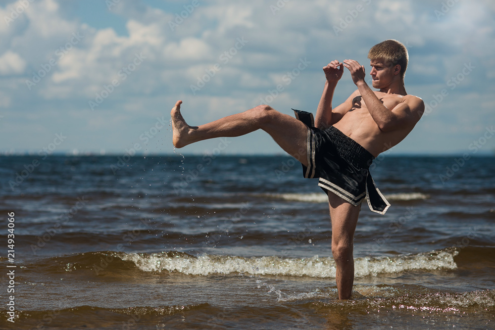 Kickboxer kicks in the open air in summer against the sea. Kickboxer kicks in the open air in summer against the sea.