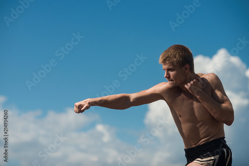 Muscular male fighter training. Boxer trains in the open air