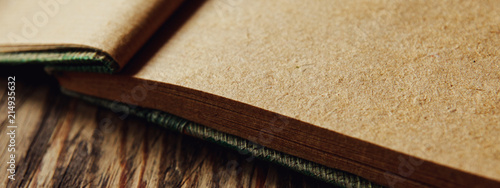 Open kraft notebook made of recycled paper on textured wooden table. Blank pages for writing