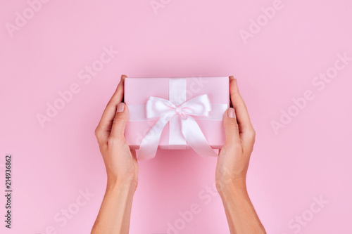 Fototapeta Naklejka Na Ścianę i Meble -  top view hand woman holding brown gift box on pink pastel color background