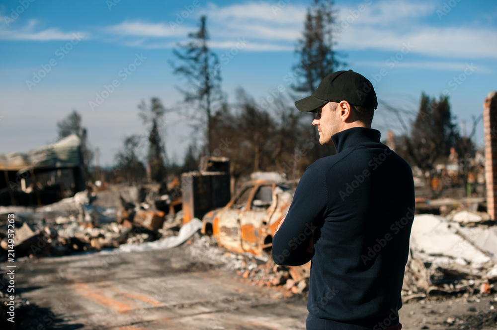Man owner checking burned and ruined house and yard after fire, consequences of fire disaster accident. Ruins after fire disaster. Man owner checking burned and ruined house and yard after fire, consequences of fire disaster accident. Ruins after fire disaster.