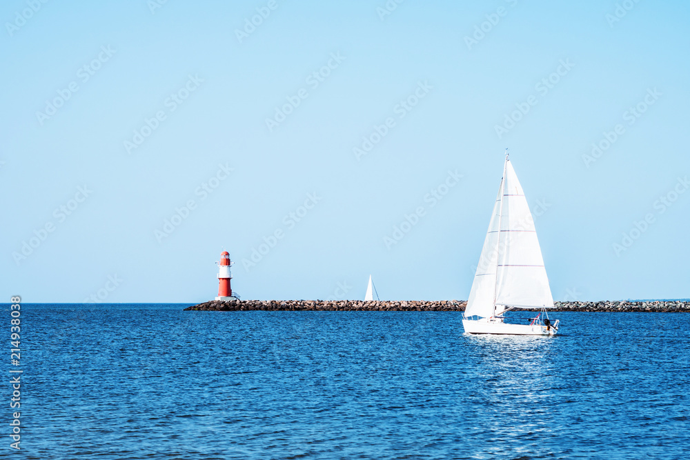 Lighthouse of Warnemuende and sailing ships and boats on the Baltic Sea at the harbor , Germany Rostock
