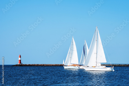Fototapeta Naklejka Na Ścianę i Meble -  Lighthouse of Warnemuende and sailing ships and boats on the Baltic Sea at the harbor , Germany Rostock