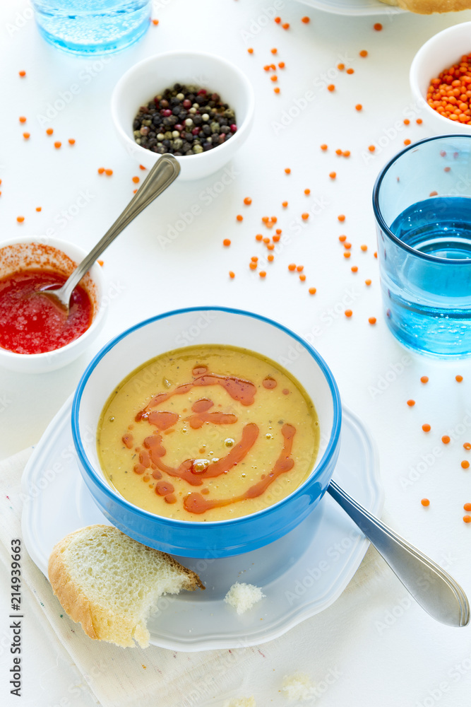 Red lentil soup with chili pepper sauce and bread on white wooden table Red lentil soup with chili pepper sauce and bread on white wooden table