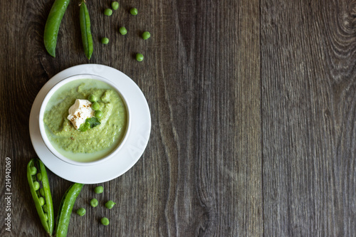 Green peas soup with spinach and cream on rustic background.