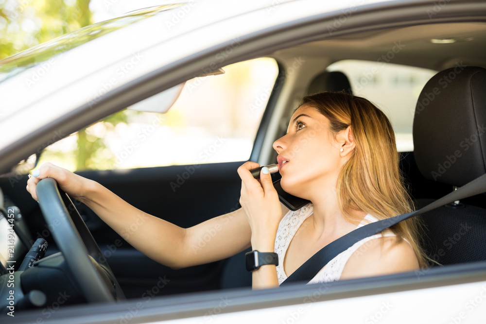 Woman in car talking on phone and doing makeup