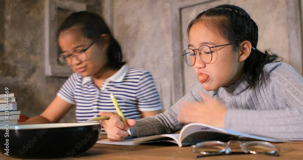 asian teenager eating snack and write school homework in living room asian teenager eating snack and write school homework in living room