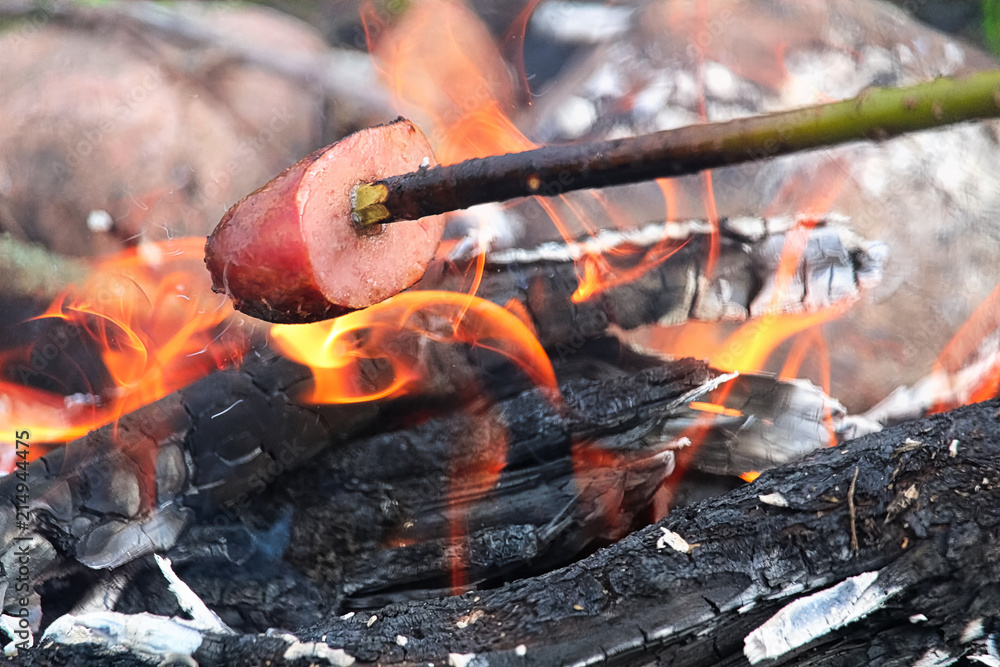 Cooking sausage on a stick over a campfire Cooking sausage on a stick over a campfire
