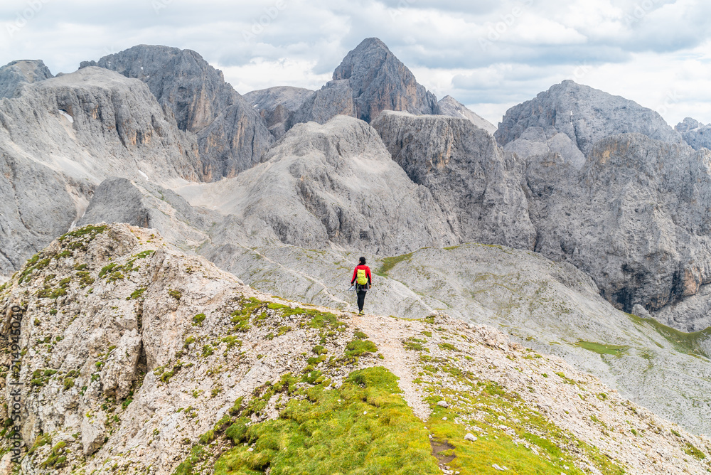 Hiker on the ridge of Dolomites Mountains in Alps, Italy. Via ferrata trail. Peole on the rocky mountains path. Travel in Dolomites. Adventure in the mountains. Mountain climber on an exposed ledge