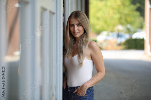 Hübsche junge blonde Frau steht lächelnd in einem Innenhof 
