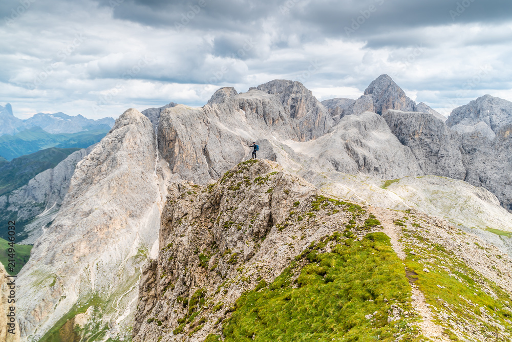 Panoramic view of a climber standing on the top of cliff in Dolomites Mountains. Italian Dolomites. Panoramic view of man walking on the ridge of the rocky mountains. 