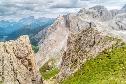 Panoramic view of a climber standing on the top of cliff in Dolomites Mountains. Italian Dolomites. Panoramic view of man walking on the ridge of the rocky mountains.  © Epic Vision