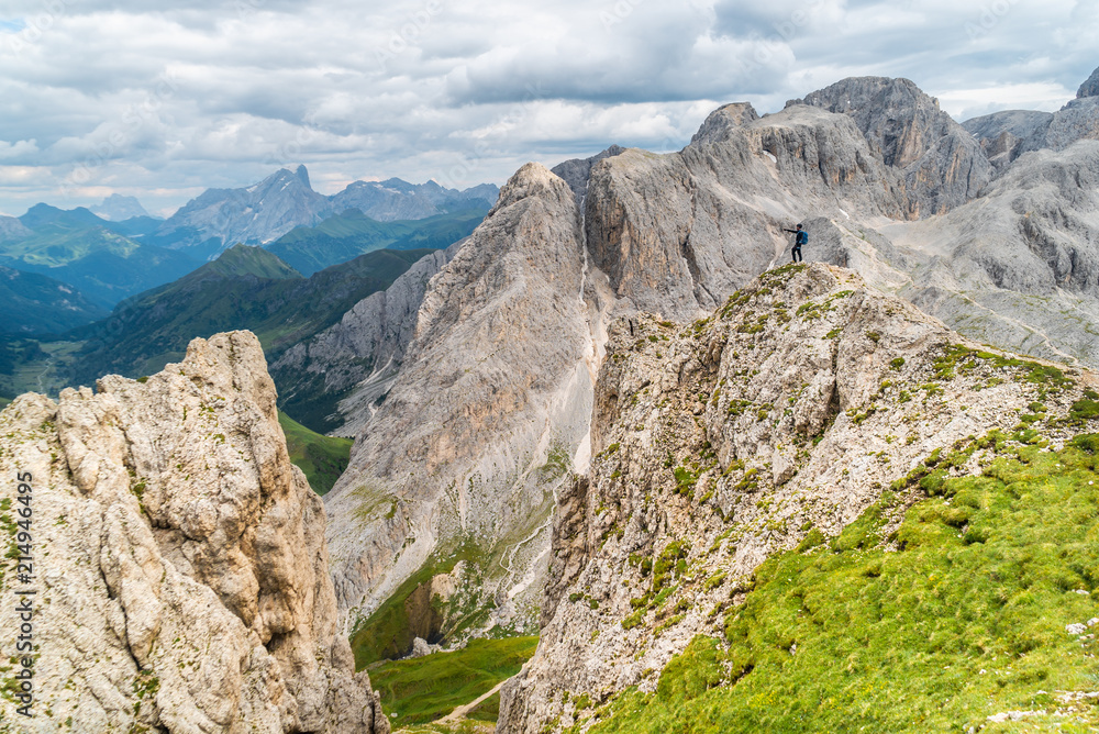 Panoramic view of a climber standing on the top of cliff in Dolomites Mountains. Italian Dolomites. Panoramic view of man walking on the ridge of the rocky mountains. 