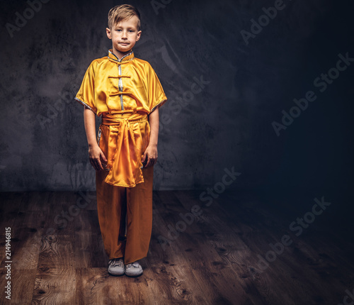 Cute boy dressed in the traditional costume of a Tibetan monk, posing at the studio.