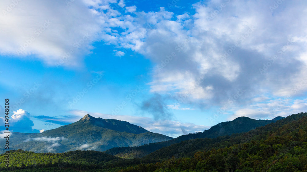 Beautiful green mountain peak landscape on a blue sky with some clouds