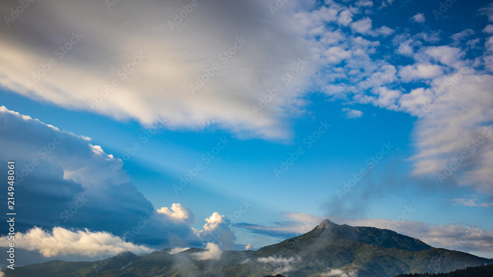 Blue sky cloudscape on a green mountain landscape