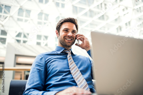 A young businessman with laptop talking on the phone. Copy space.