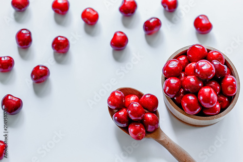 Red ripe cherries with wooden spoon on white background. Flat lay. Food concept. photo