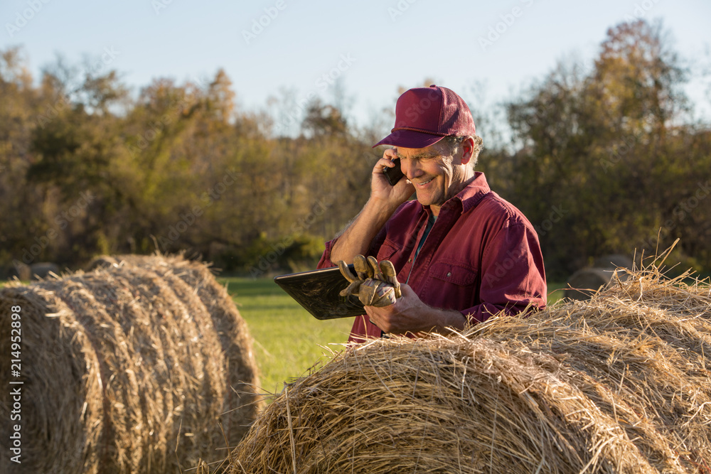 Farmer using tablet and talking on mobile phone Farmer using tablet and talking on mobile phone