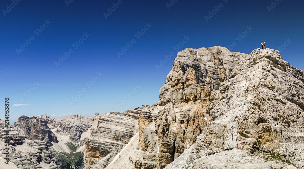 Via ferrata Tofana di Mezzo climbers on the ridge in the Dolomites, Group of climbers on the mountain top, Dolomite Alps, Italy. Silhouette of people climbing the mountain. Tiny Man Big Landscape