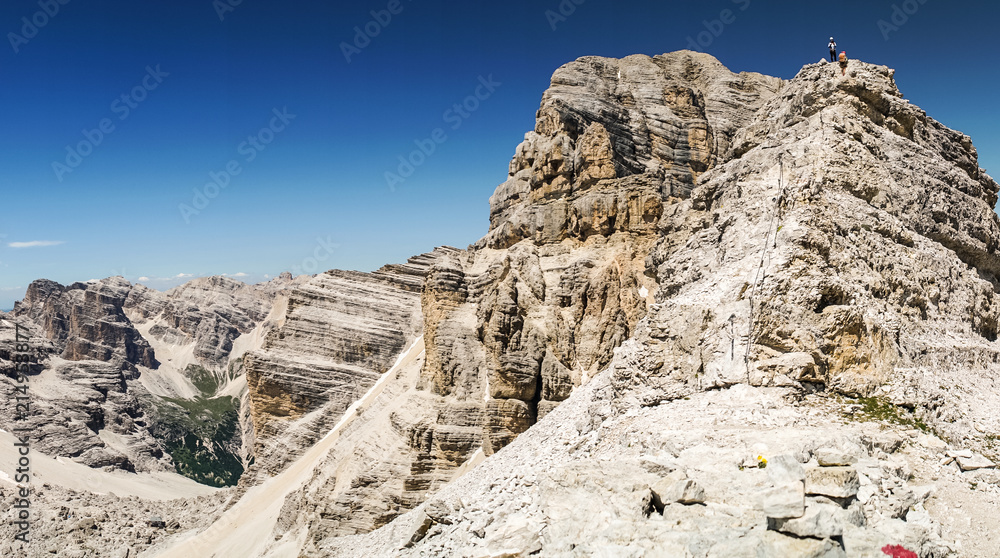 Climbers silhouette standing on a cliff in Dolomites. Tofana di Mezzo, Punta Anna, Italy. Man Celebrate success on top of the mountain Hiker standing on rocky ridge and enjoying  the view in Dolomites