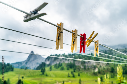 Clothes pins on a clothes line rope. clothespins hanging hook. Clothes pins lined up on a wire. Fresh green meadow and mountains on the background. Wooden clothes pins on a string outside laundry
