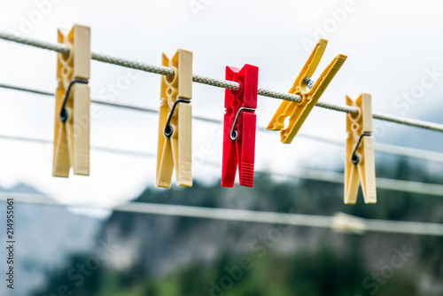 Clothes pins on a clothes line rope. clothespins hanging hook. Clothes pins lined up on a wire. Fresh green meadow and mountains on the background. Wooden clothes pins on a string outside laundry