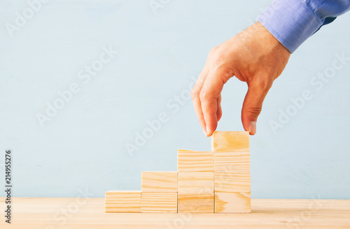 businessman arranging wood blocks stacking as step stairs. success and development concept.