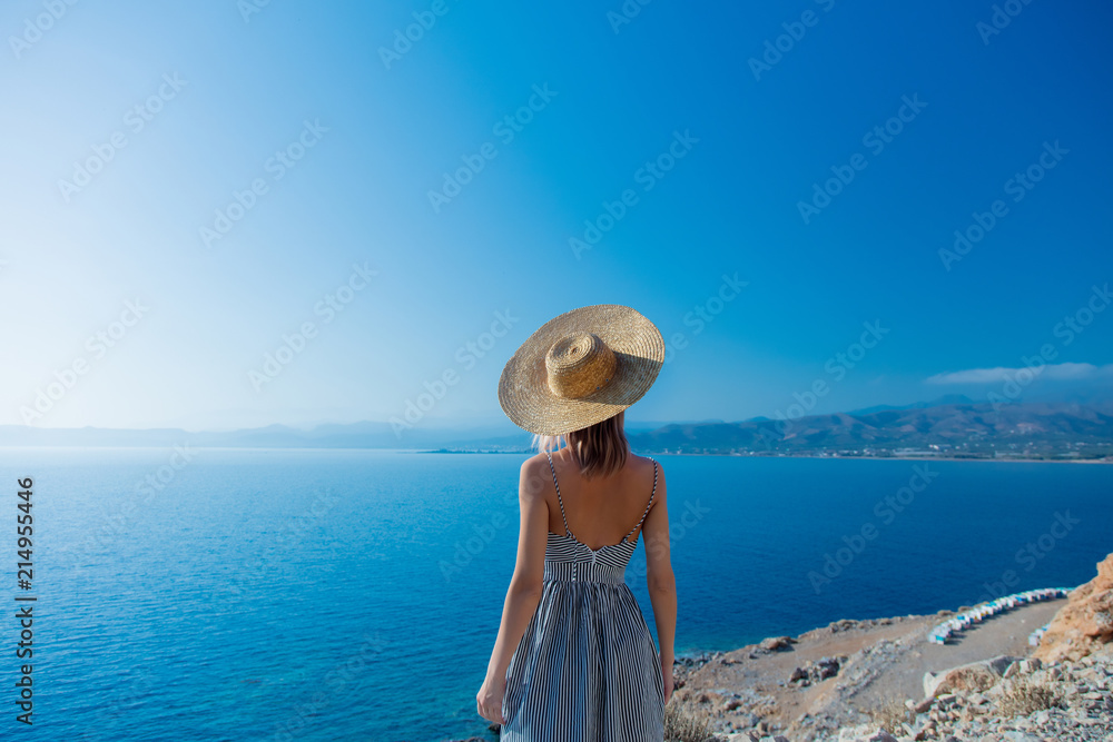 Young redhead girl in hat and dress with sea coastline on Balos, Crete, Greece