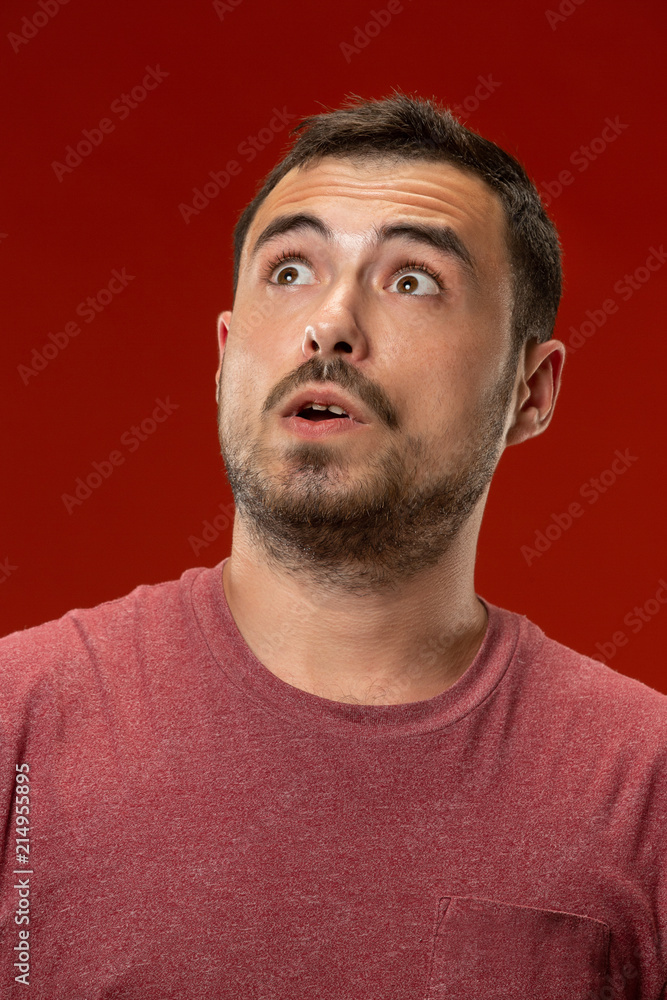 The young attractive man looking suprised isolated on red The young attractive man looking suprised isolated on red