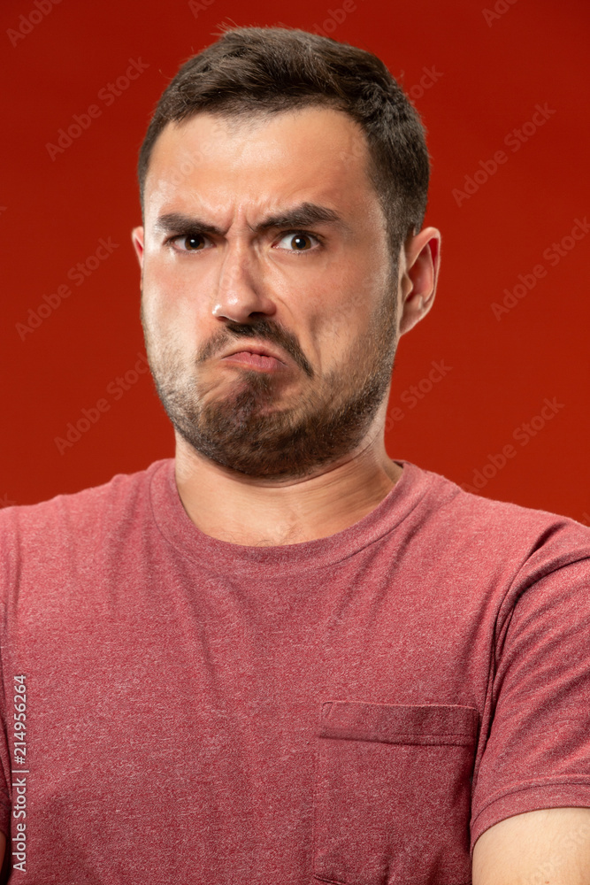 The young emotional angry man screaming on red studio background The young emotional angry man screaming on red studio background