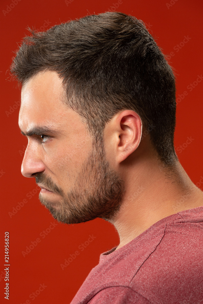 The young emotional angry man screaming on red studio background The young emotional angry man screaming on red studio background