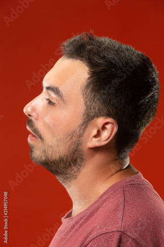 Beautiful man looking suprised and bewildered isolated on red