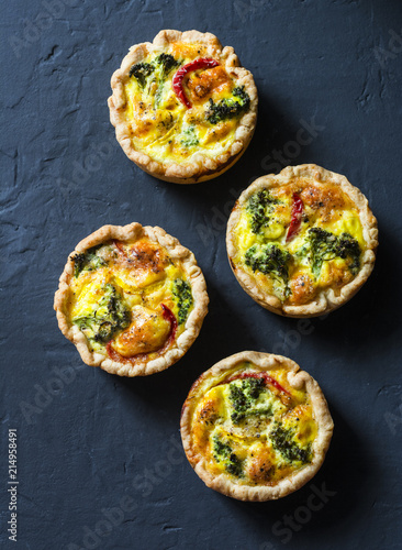 Broccoli cheddar mini savory pies on dark background, top view. Delicious appetizers, snack, tapas