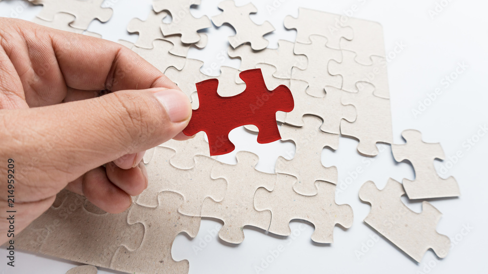 Hand put missing jigsaw puzzle into the paper board Hand put missing jigsaw puzzle into the paper board