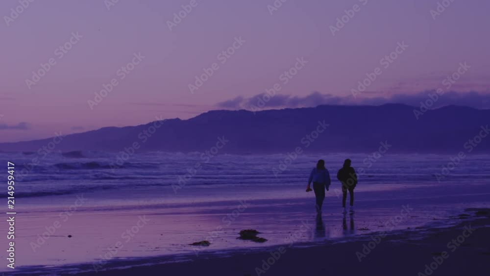Two female friends enjoying the sunset by walking down the beach at night. Slowmotion. 4K UHD 120fps 16-bit HDR. Shot on RED. Two female friends enjoying the sunset by walking down the beach at night. Slowmotion. 4K UHD 120fps 16-bit HDR. Shot on RED.