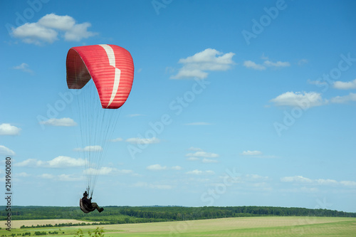 Paragliding over the green field in summer sunny day. One paraglider fly over green field near Dnister river in Ukraine.