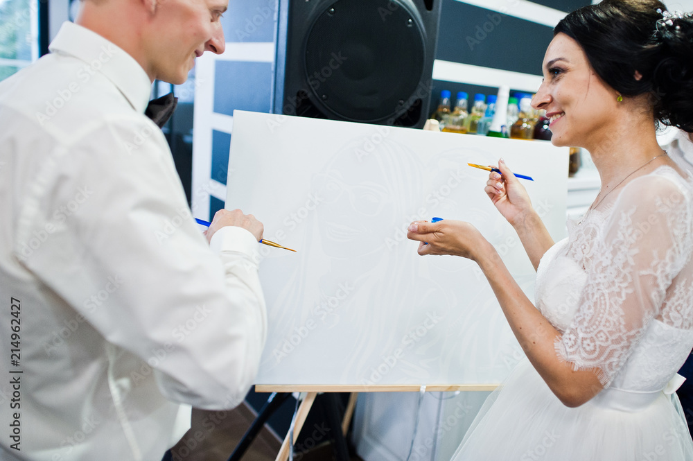 Wedding couple painting something on the canvas in the restaurant. Wedding couple painting something on the canvas in the restaurant.