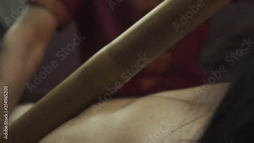 Young woman lying on spa bed recives massage with bamboo sticks photo