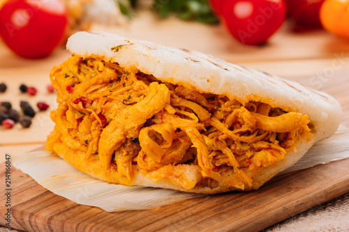 Delicious and provocative arepa with crushed chicken and around it some ingredients of its preparation