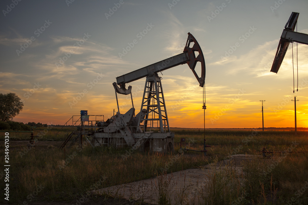 The oil pump, industrial equipment. Oil rocking at sunset in Russia, Republic of Bashkortostan The oil pump, industrial equipment. Oil rocking at sunset in Russia, Republic of Bashkortostan