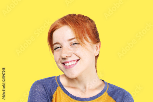 Photography Beautiful redheaded young woman with satisfied facial expression, isolated on yellow background