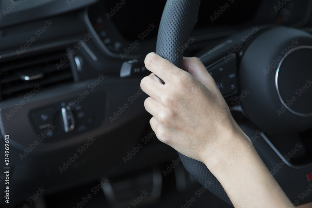 The hand of a girl with a stylish manicure lies on the handlebars in a saloon car.