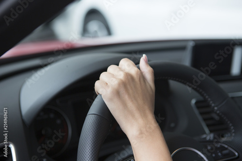 The hand of a girl with a stylish manicure lies on the handlebars in a saloon car.