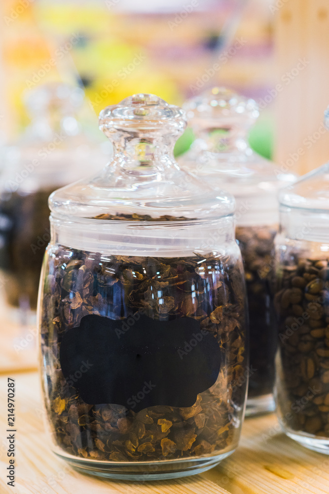 Traditional black coffee beans in a glass jar on the counter of a small market or store. Traditional black coffee beans in a glass jar on the counter of a small market or store.