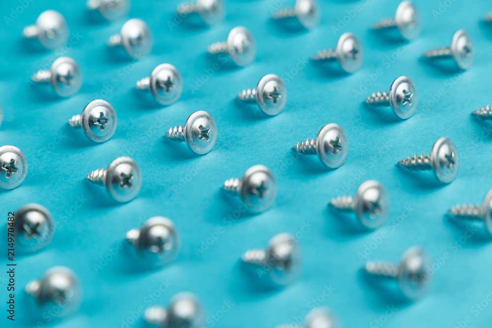 Tapping screws made of steel on blue background. Concept.